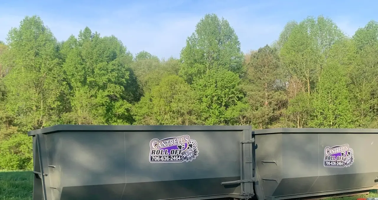 Green Cantrell's roll-off dumpster with purple logo sitting on grass
