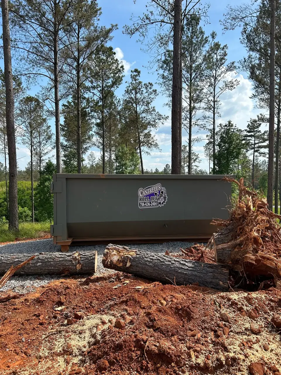 Cantrell's roll-off dumpster at a land-clearing job site with logs