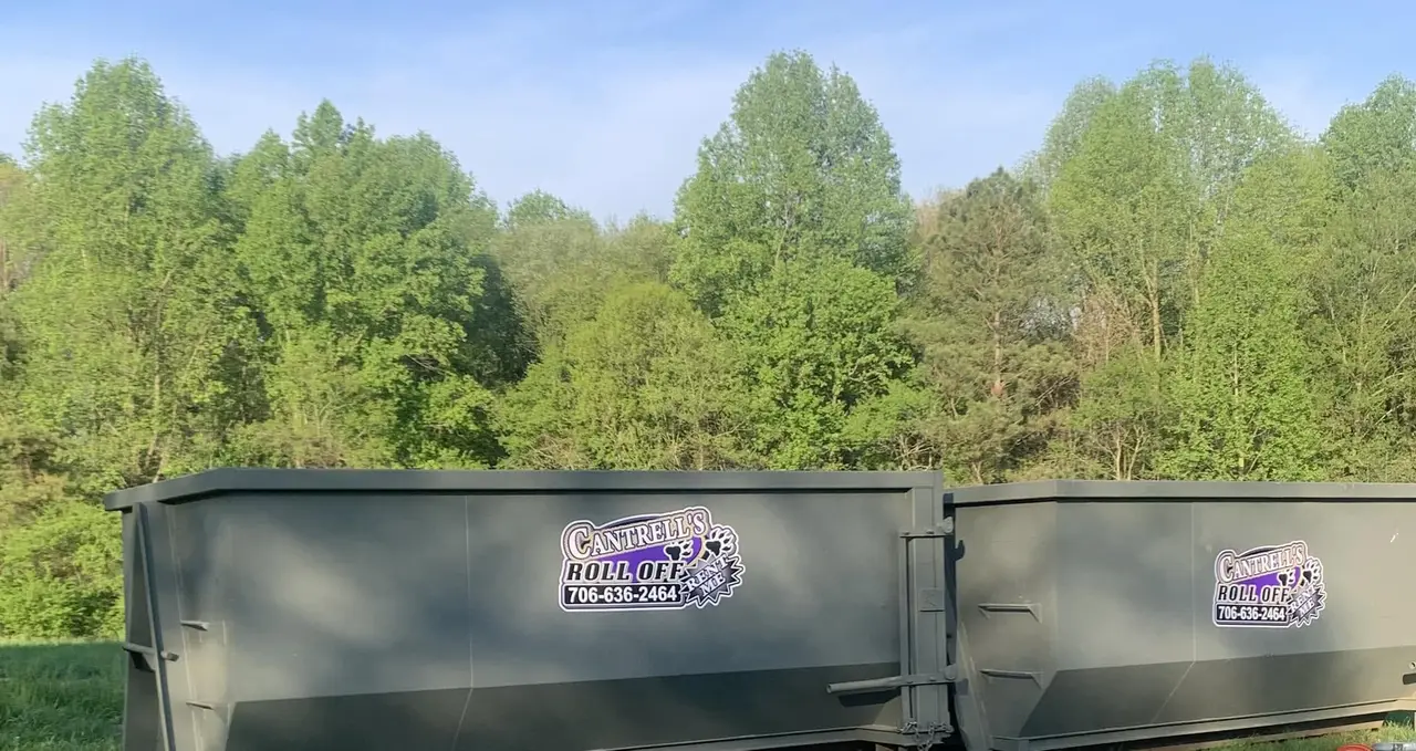 Green roll-off dumpster branded with the Cantrell's logo on a lawn
