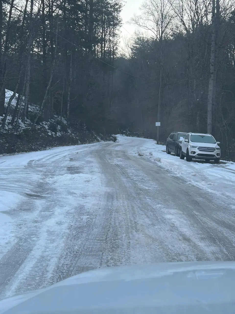 Snow and ice covering a wooded Gilmer County road on the winter route, seen from the truck
