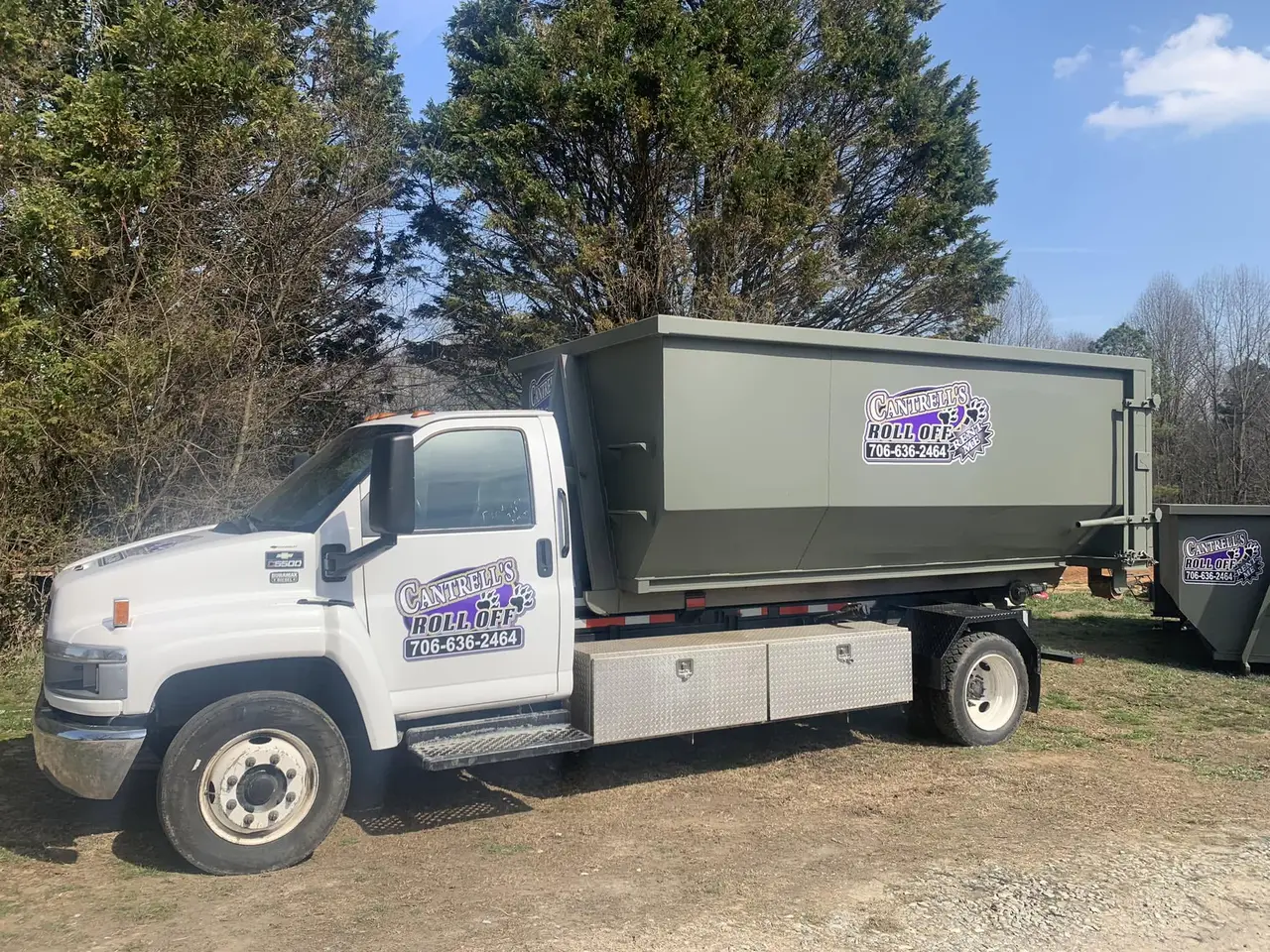 Cantrell's roll-off truck hauling a green dumpster with the purple Cantrell's logo