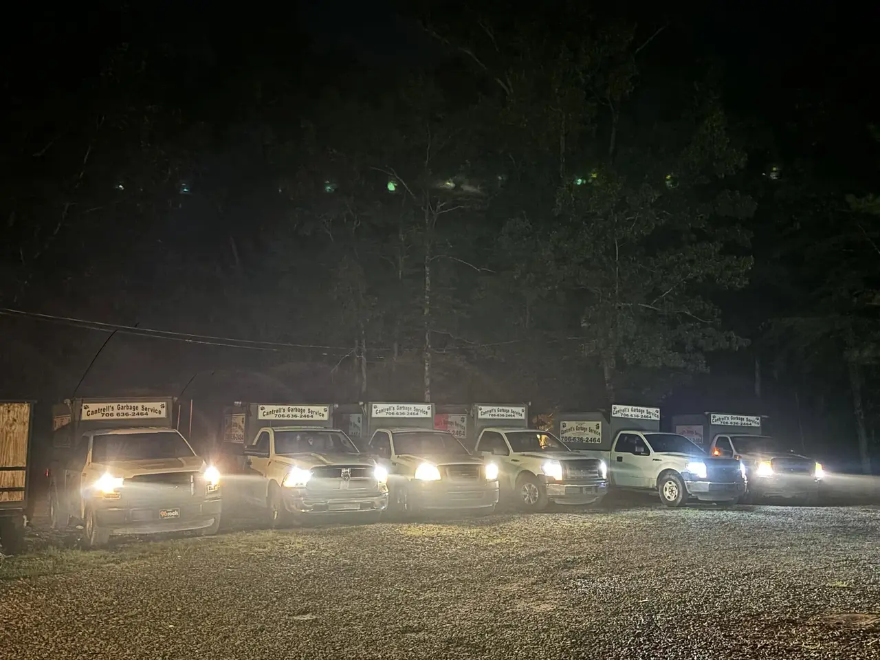 Cantrell's fleet of garbage trucks lined up at night with headlights on